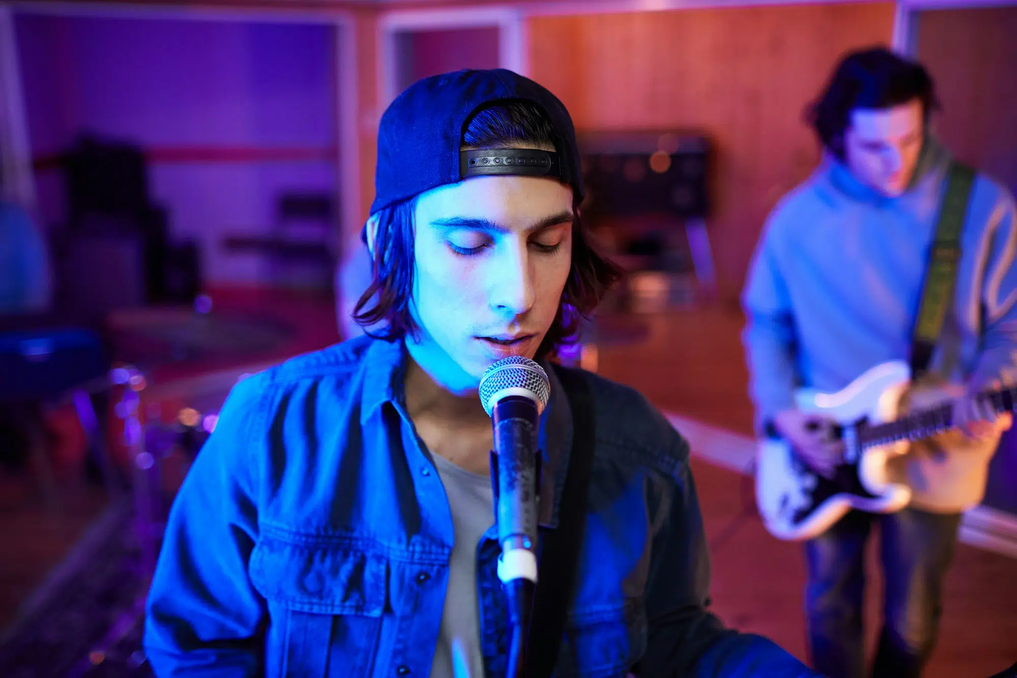 Cantante ensayando con su grupo de música después de haber elegido y comprado el mejor micrófono para su voz